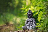 Buddha statue outside on nature and green background with copy space