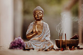 Close up of a Buddha figurine and smoky incense with gong and amethyst