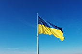 The flag of Ukraine develops on a flagpole against a background of clear sky