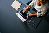High Angle View Of Unrecognizable Woman Typing Business Report On A Laptop Keyboard In The Cafe