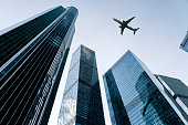 Airplane flying on business skyscrapers of financial center. Travel, economy, cargo, transportation concept