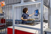 Young man holding a box and updating package details on computer at automated warehouse