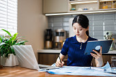 young female designer works on a laptop in a dining room