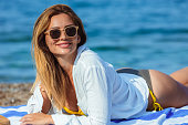 Young beautiful woman with sunglasses laying at the beach.