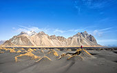 Tourist photographer at Stokksnes admiring Vestrahorn. Iceland.