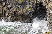 Basalt columns with sea cave and the rugged coastline of Arnarstapi in the Snaefellsnes Peninsula, western Iceland. Close up detail of the crashing waves along the cliff.