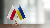 Polish And Ukrainian Flag Pair On A Desk Over Defocused Background