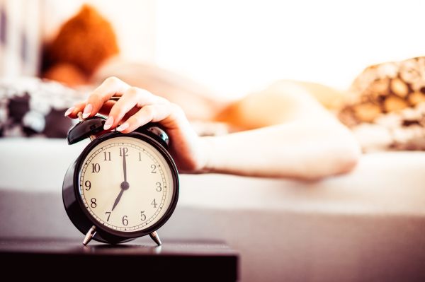 Woman Shutting Off Ringing Alarm Clock From Bed Free Stock Photo