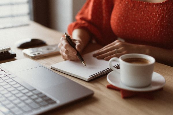 Woman Sitting at a Wooden Table and Writing in a Diary at Home Free Stock Photo