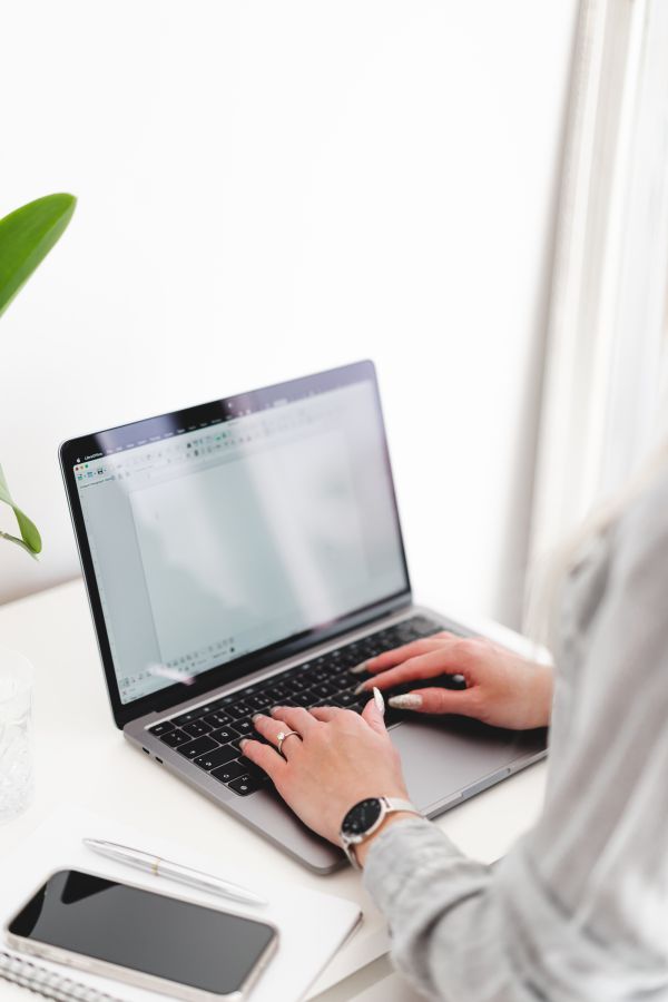 Woman Writing on Her Laptop in a Bright White Office Free Stock Photo