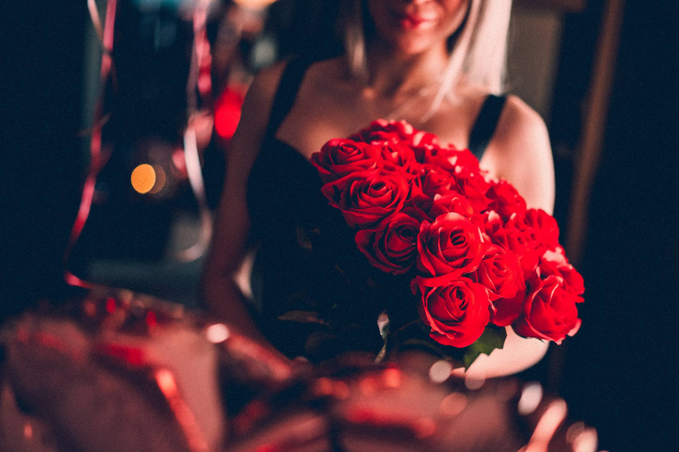 Young Woman Holding a Bouquet of Red Roses on a Date Night Free Photo